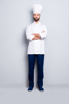 Full size fullbody portrait of  harsh virile chef cook with stubble in beret, having his arms crossed, isolated over grey background, looking at camera