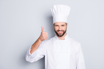 Portrait of cheerful joyful chef cook with stubble in beret, white outfit showing thumb up, approve...