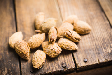 Roasted almonds in shell on the rustic background. Selective focus.
