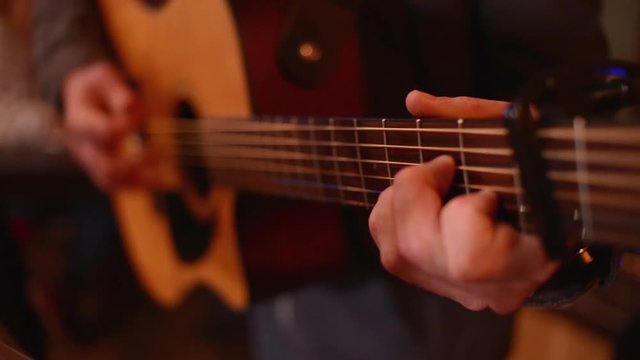 Close-up a Man Musician Hand play on a Guitar Strings in a Restaurant Evening
