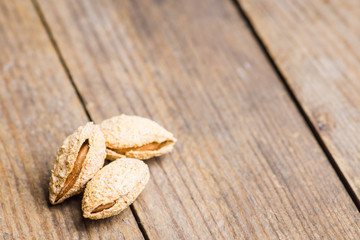 Roasted almonds in shell on the rustic background. Selective focus.
