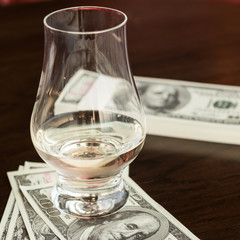 Exclusive Scott and Japanese whisky with dollars bank notes on wooden table in luxury bar, tip for good service.  Film tones conception.