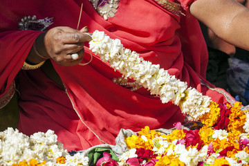 Fototapeta na wymiar Indian female hands making fresh flower necklace for selling