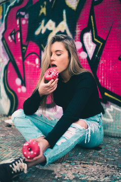 Young woman eating donuts on street