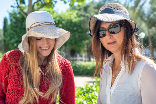 Two female tourists with straw hats enjoying outdoor city life