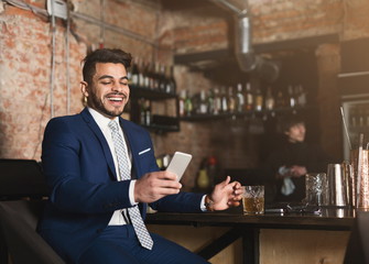 Happy businessman resting in bar after working day