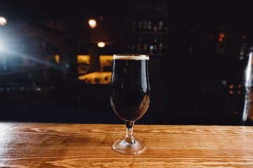 Glass glass with cold unfiltered beer on background of bar.
