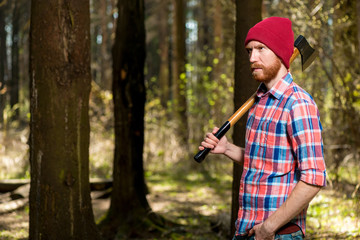 bearded stern forester with an ax walking in the woods