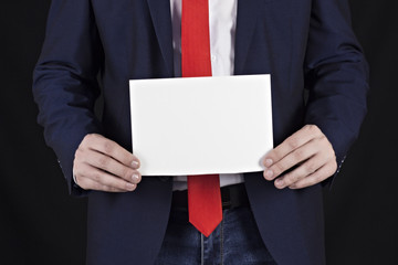 Businessman in a jacket holding a blank sheet in his hand