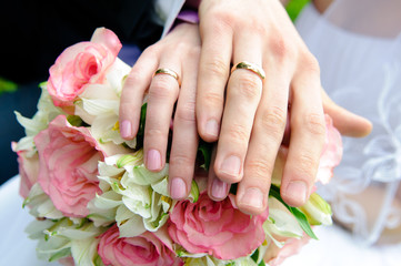 Obraz na płótnie Canvas Hands of newlyweds with wedding rings on a bouquet of the bride. 