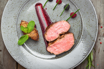 Medallions of veal, with sauce on a plate. Wooden background