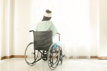 Fototapeta na wymiar Young woman in hospital wheel chair. Looking at window. Beautiful chinese woman. Medical, health insurance concept.