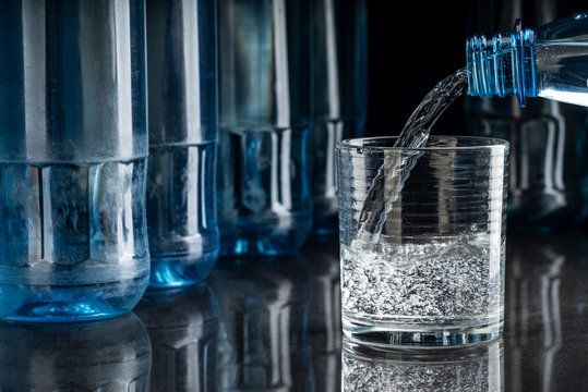 Mineralwasser in ein Glas eingeschenkt auf spiegelndem Tisch, Hintergrund