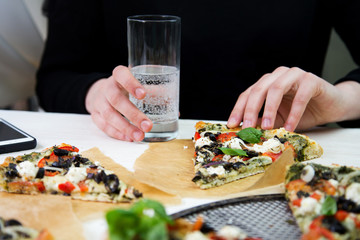Fresh baked italian vegetarian pizza being eaten with a glass of sparkling water by a girl at a restaurant