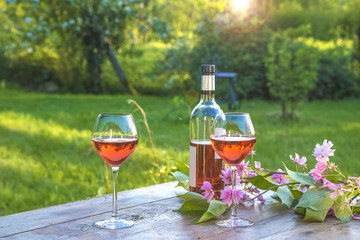 French art of living/Bottle of pink wine and two wineglasses on a rustic wooden table in a spring...