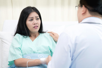 Doctor with patient. Routine health check and holding hands. Male medical doctor with young chinese woman.