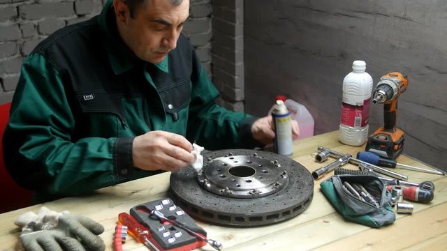 Un homme degraisse et d&eacute;poussi&egrave;re un disque de frein