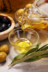 Bottle virgin olive oil and oil in a bowl with some olives