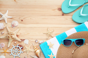 Different seashells with towels and flip flops on brown wooden table