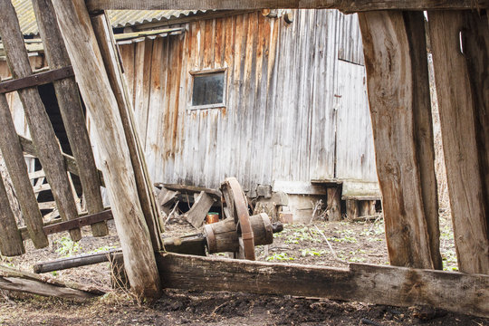 Ruins of old ranch in countryside. Broken wooden barn and wheel from the cart