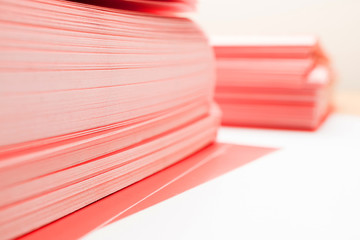 corners of a stack of red paper on a table, two piles of dense paper