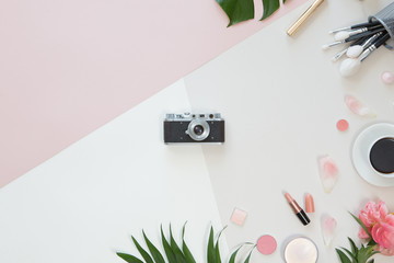 Top view of background with Tropical palm tree leaf, vintage photo camera, flowers and make up cosmetics on a trendy pastel background, flat lay