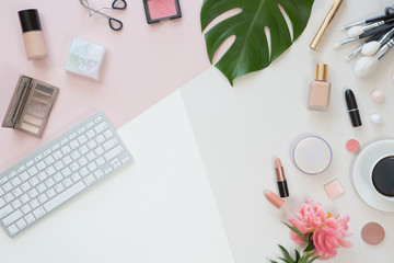 Pastel office table desk with computer laptop, green palm leaves, flowers, clipboard and beauty accessories, top view and flat lay. Home fashion women office workspace isolated on pink background.