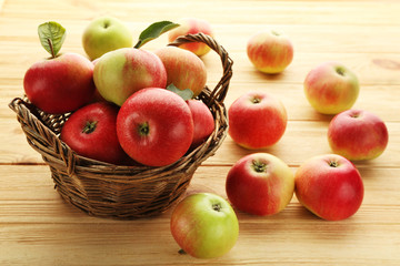 Ripe and sweet apples in basket on wooden table