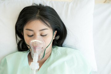 Young patient alone in bed. Sleeping in hospital bed. Oxygen mask on her face. Young beautiful...