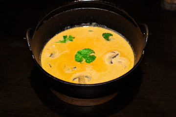 В японском ресторане, желтый суп с грибами в чугунном горшке.