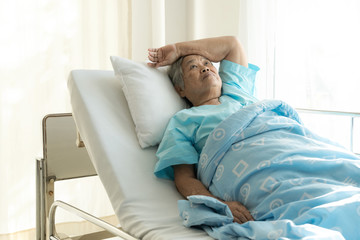 Elderly patient alone in bed. Alone and stress, missing her grand children. Looking at ceiling. Very senior, old chinese woman.