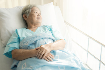 Elderly patient alone in bed. Alone and stress, missing her grand children. Looking at window. Very...