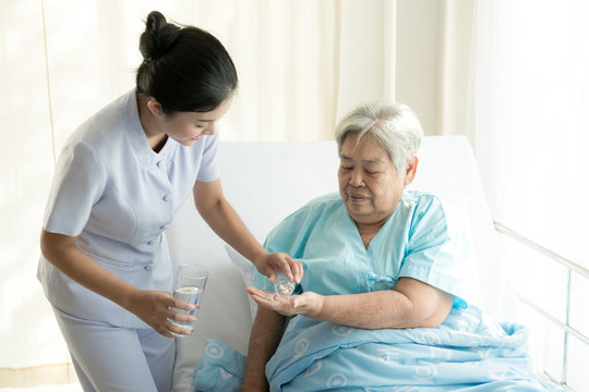 Nurse with patient. Routine health check and giving medication. Female nurse with senior chinese woman.
