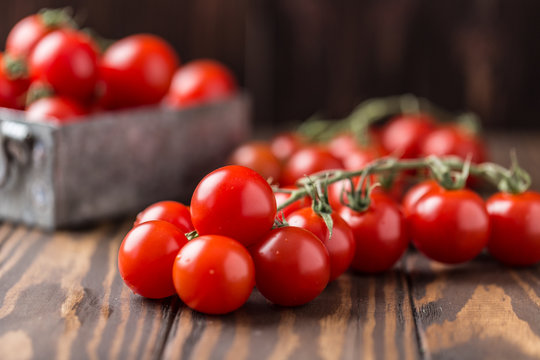 Small red cherry tomatoes on rustic background. Cherry tomatoes on the vine
