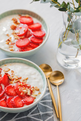 Close-up of bowls with coconut yoghurt, fresh strawberries and almonds. The concept of breakfast and a healthy lifestyle. Scandinavian style.
