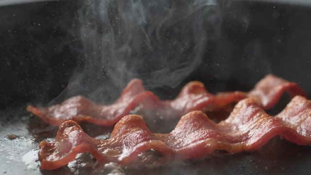 Camera follows cooking bacon on grill. Shot with high speed camera, phantom flex 4K. Slow Motion.