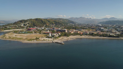 Obraz premium Linia brzegowa z plażą i latarnią morską, góry. Widok z lotu ptaka: Wybrzeże morskie z hotelami, kurortami, zatoką Subic, Filipiny, Luzon