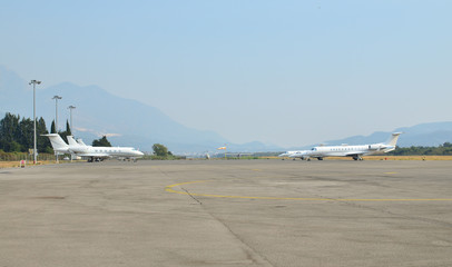 Two airplanes parked on an empty runway with a landscape in a background
