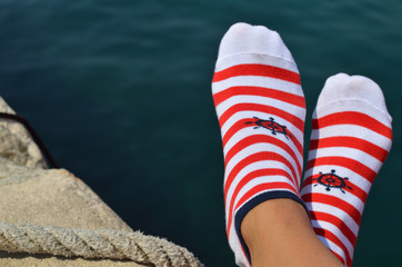 Feet in marine style socks against blue sea surface