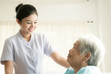 Nurse with patient. Routine health check and assisting elderly patient to walk. Female nurse with...