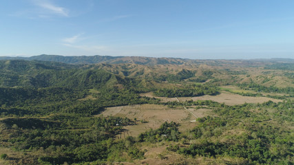 Fototapeta premium Mountain valley with village, farmland in the Philippines, Luzon. Aerial view: Mountain valley with green trees and river.