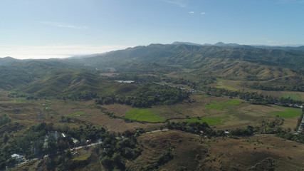 Naklejka premium Mountain valley with village, farmland in the Philippines, Luzon. Aerial view: Mountain valley with green trees and river.