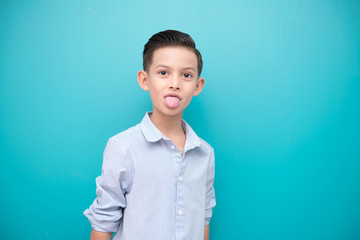 Young boy isolated in blue. Handsome early teenage boy portrait. Happy smile naughty pose.