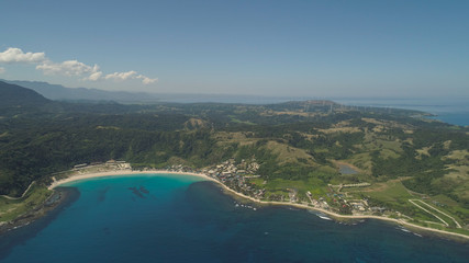 Aerial view of beautiful tropical beach with turquoise water in blue lagoon, Pagudpud, Philippines. Ocean coastline with sandy beach. Tropical landscape in Asia.