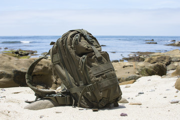 Adventure backpack on sand with ocean in background