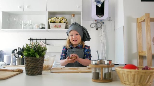 Little girl baker rolls out the dough and talking