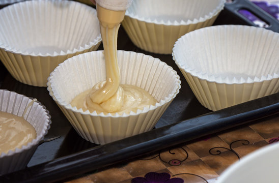 making muffins, filling the cups with batter
