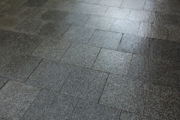 Wet paving slabs made of a marble chips after the rain
