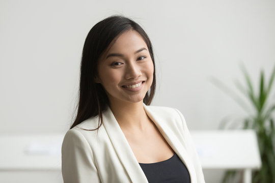 Happy Asian office worker in formal wear smiling to camera posing for company business catalogue, making portrait photo. Confident businesswoman laughing with bright wide smile