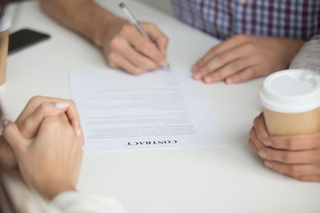 Close up of husband hands signing contract of house purchase, taking loan or mortgage. Couple closing deal of renting flat, putting signature on agreement. Concept of life changes, dreams come true